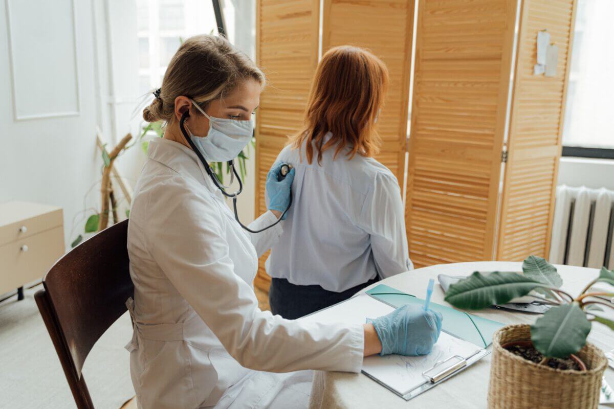 Caregiver taking notes while listening to a patient's lungs